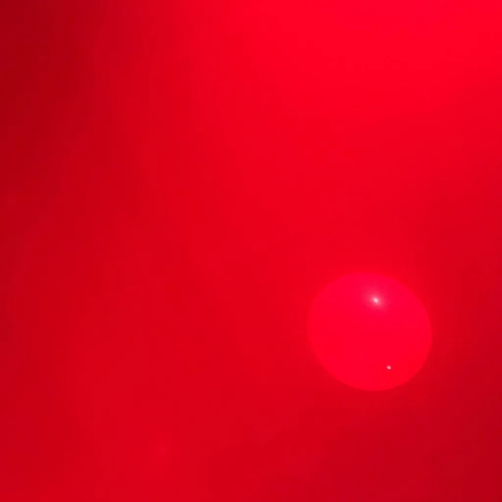 A vibrant red field dominates the composition, featuring a smooth, glowing red circle positioned in the lower right quadrant.