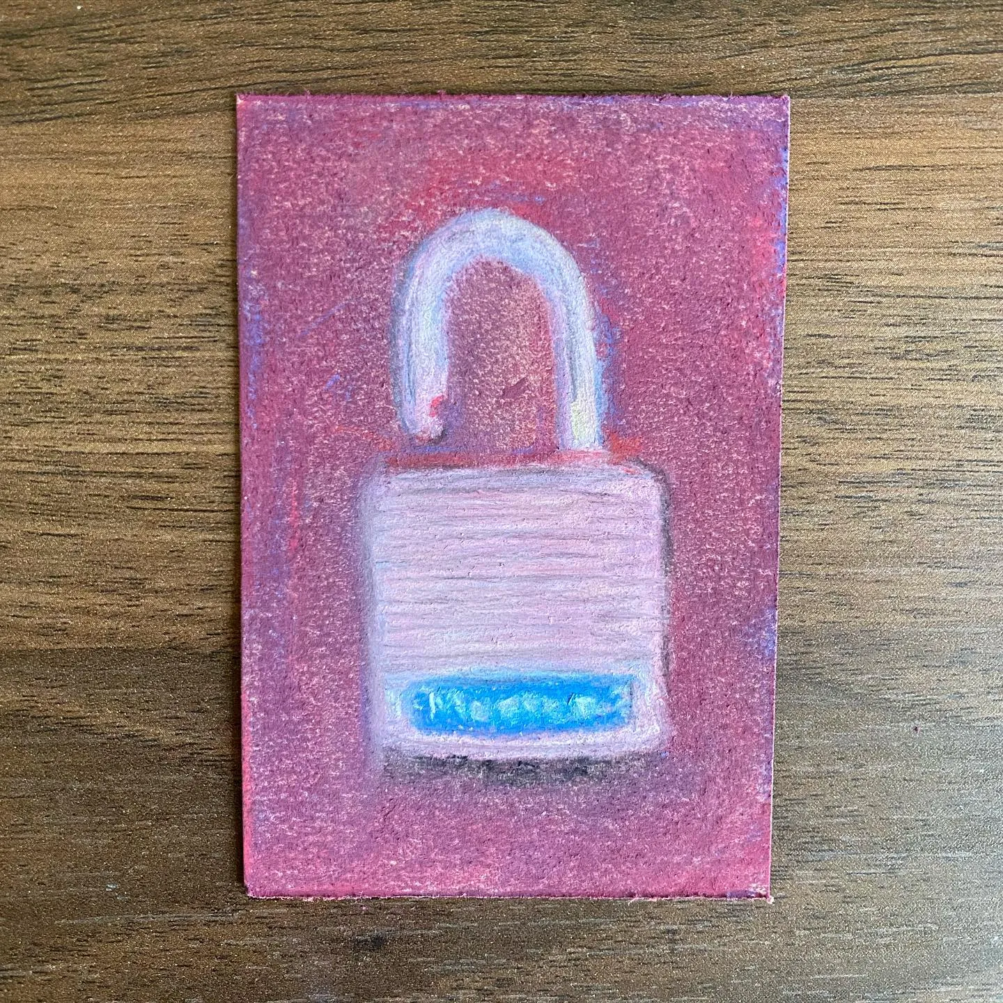 A square artwork features a stylized white padlock with a blue rectangular base, set against a textured pink background.