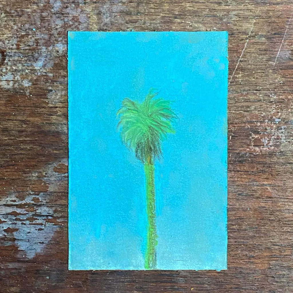 A single, tall palm tree with bright green fronds stands centered against a vibrant blue sky that fades from light to deep turquoise.