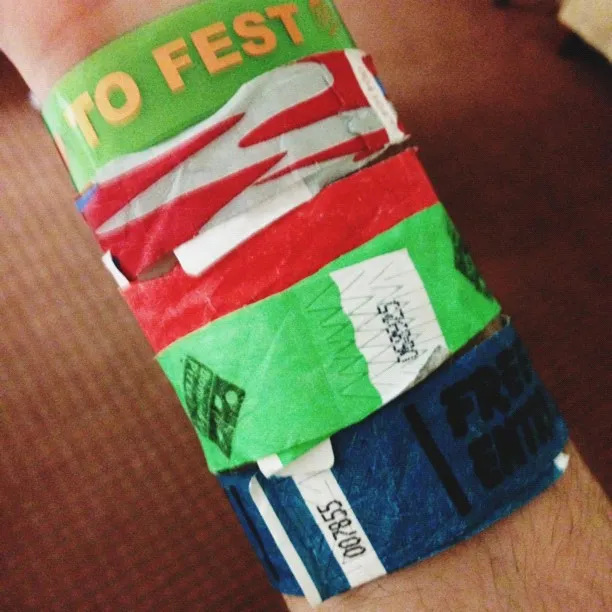 A stack of layered, printed bands wrapped around a wrist, featuring colors including red, white, green, and blue, with visible text and numbers.