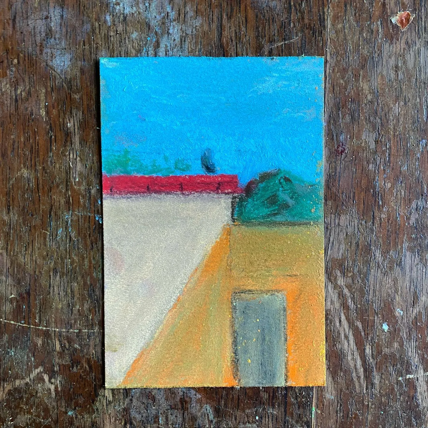 A stylized landscape composition showing a bright blue sky, a white building with a red roof, dark green foliage, and a yellow-orange ground plane containing a rectangular shape.