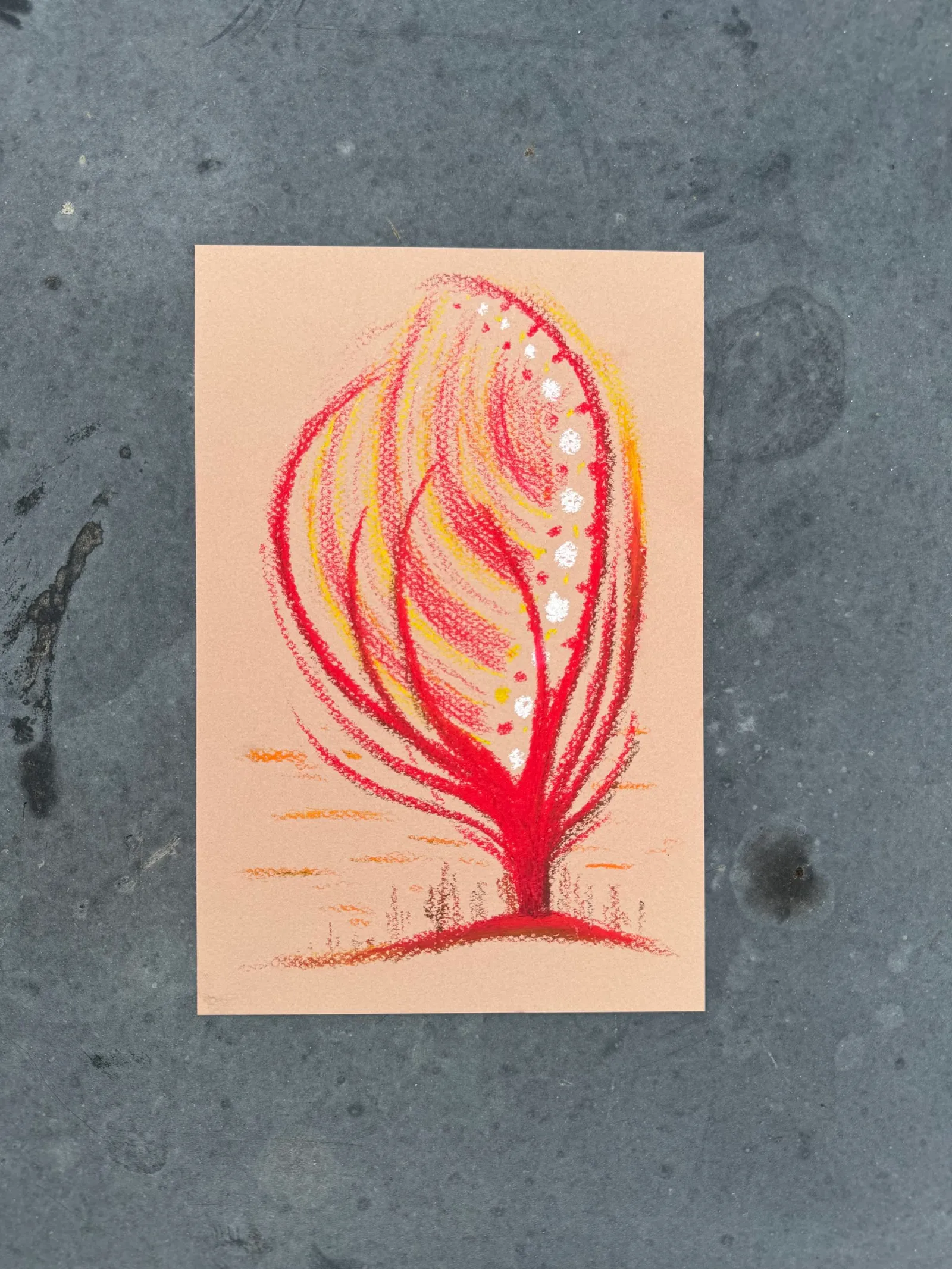 A stylized, vertical drawing of a plant features a deep red base and radiating yellow and orange strokes, accented by small white spots, all set against a pale background.