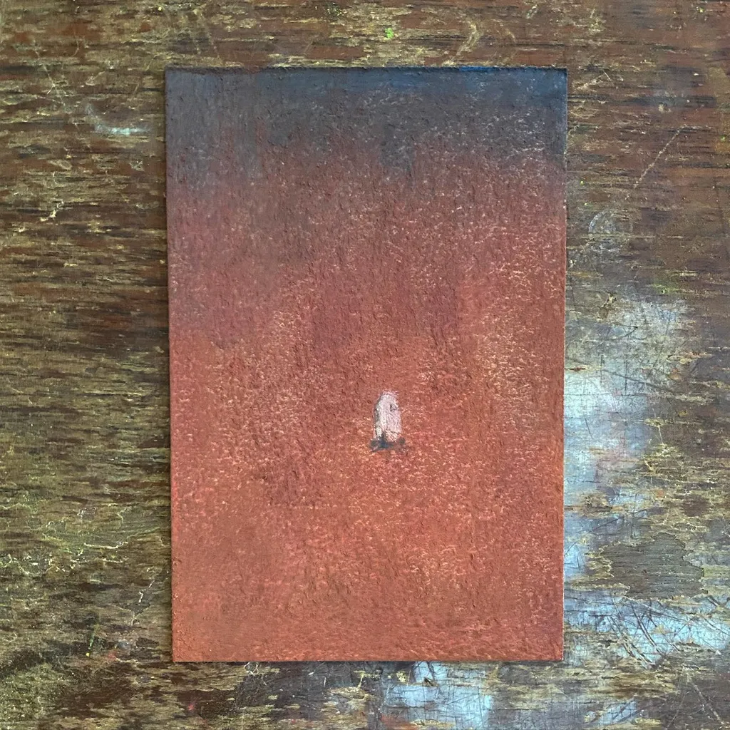 A reddish-brown rectangular panel, showing a gradient from dark to light, rests on a highly textured, dark wooden surface, marked by a small vertical streak.