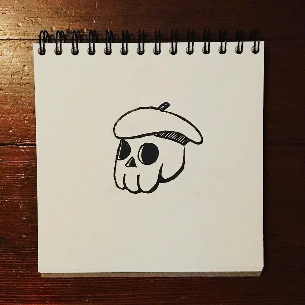A simple black line drawing of a cartoon skull wearing a small hat, centered on a white spiral notepad resting on dark wood.
