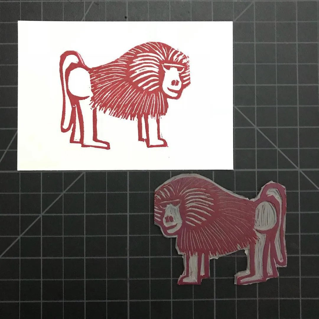 A red line drawing of a stylized lion on white paper is paired with a solid red cutout of the same animal on a grid background.